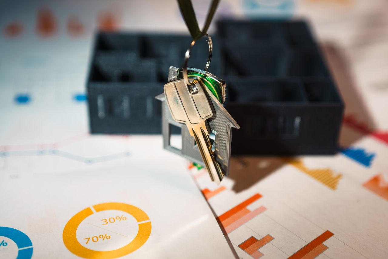 services-03 Real estate keys on house keychain with financial graphs, symbolizing property investment.