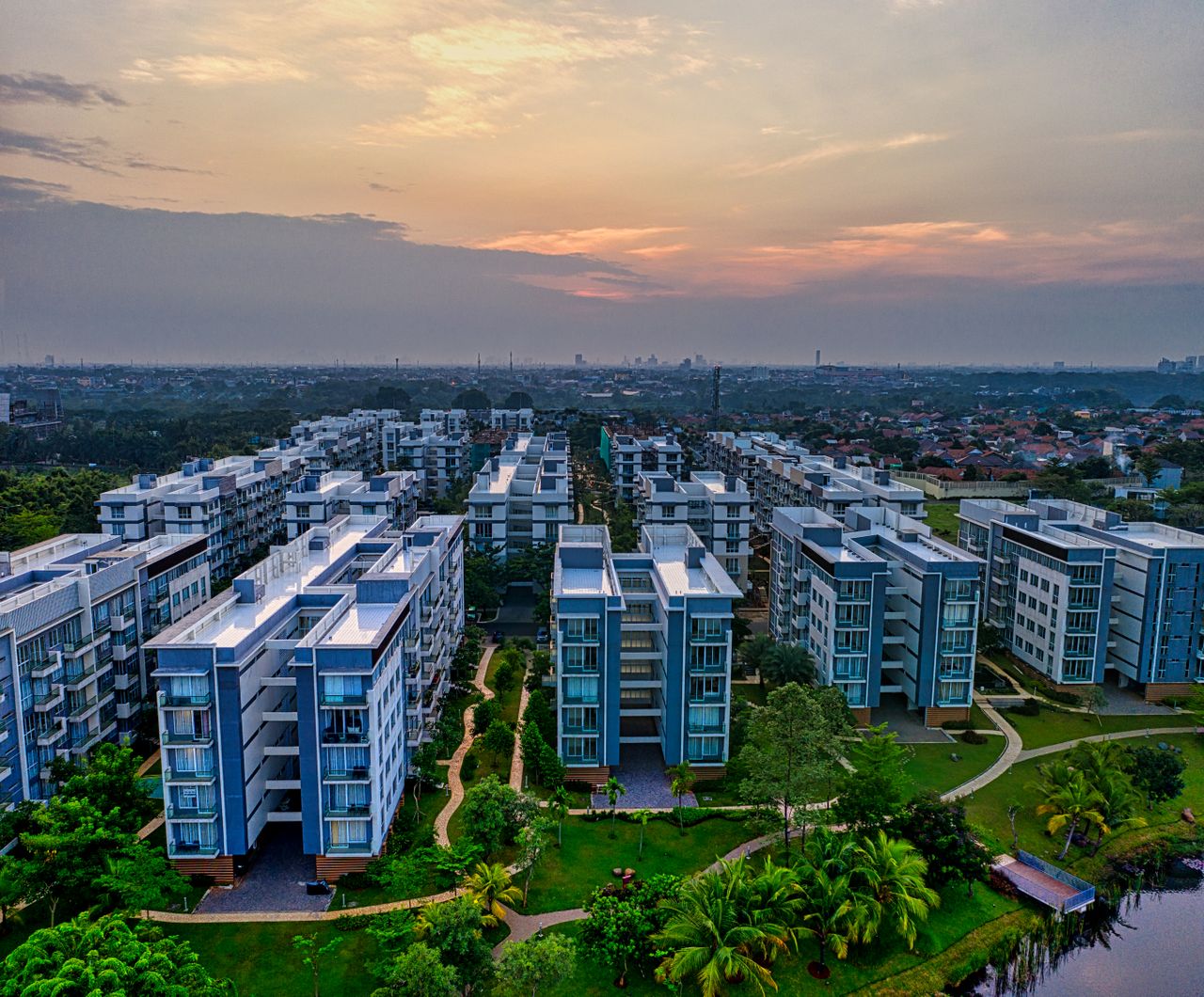 services-04 Living district with typical buildings on green shore of river under cloudy sunset sky